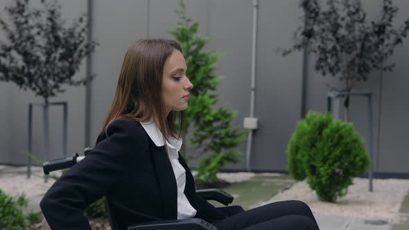 Crop View of Female Person in Suit Pushing Herself on Wheel Chair at Street