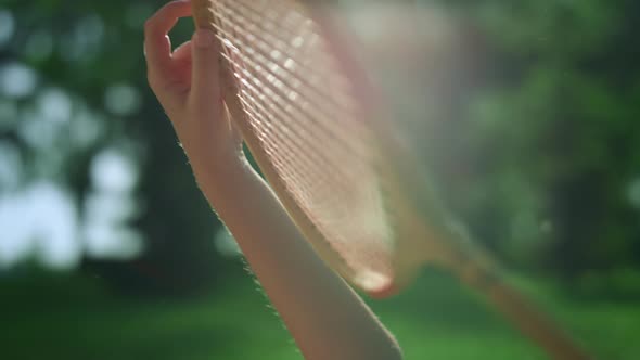 Closeup Hand Holding Wooden Badminton Racket in Golden Sunlight in Park