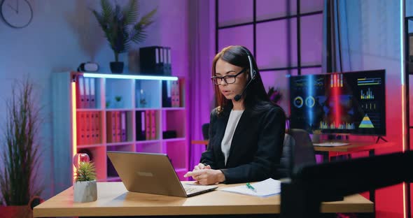 Businesswoman in Headset Holding Online Meeting with Her Subordinates on Laptop