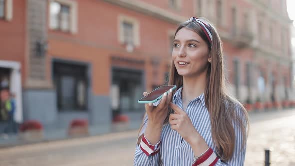Young Beautiful Woman with Headband on It Wearing Fashionable Striped Dress Using Her Smartphone