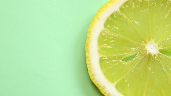 Slice of Lemon Rotating Close-Up on Green Background