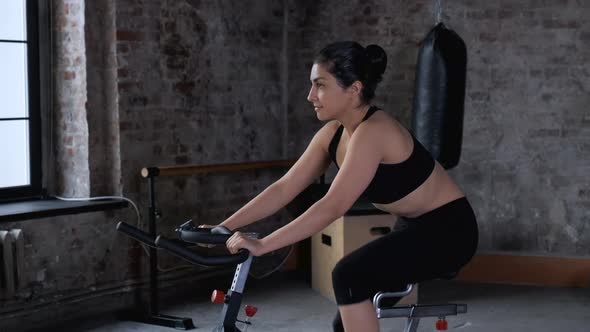 Young Athletic Indian Woman Doing a Workout, Engaged in Cycling Dressed in Sportswear Black Top