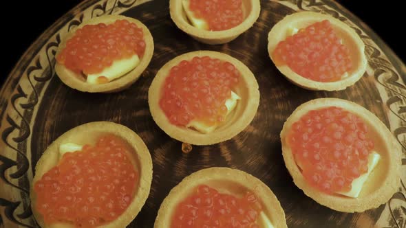 Red Caviar Is Put with a Spoon on Tartlets. Preparation of Snacks with Red Caviar. Top View