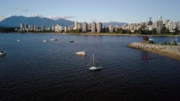 Famous Kitsilano Beach With Sailboats And People Kayaking On The Ocean. Downtown Skyline And English