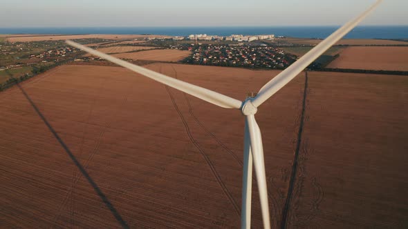 Aerial View of a Windmill with a Village and Farmland in the Background on a Warm Summer Evening