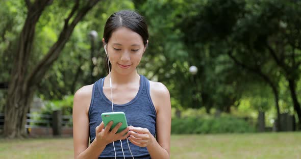 Sport Woman Listen to Music on Cellphone with Earphone in The Park