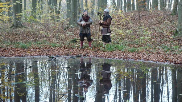 Viking warriors talking by a pond's edge