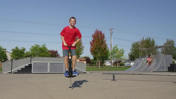 Boy jumping on Pogo stick at park