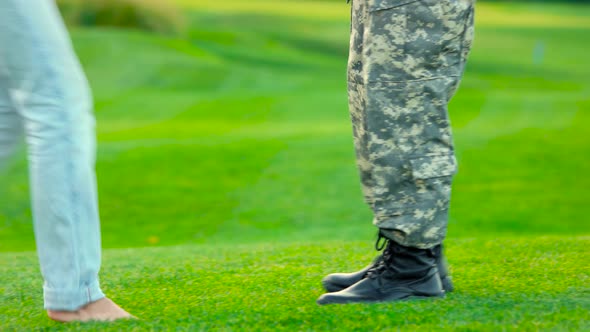 Woman Stand on Her Toes To Kiss Her Soldier Boyfriend.