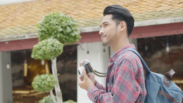 Smiling of handsome young Asian man tourists traveling and taking a photo in temple Thailand.