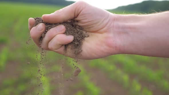 Farmer Holds Handful of Earth in His Hand Sifting It Through His Fingers