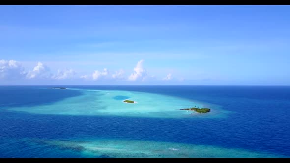 Aerial flying over panorama of idyllic island beach vacation by blue lagoon with white sandy backgro