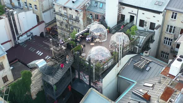 Rooftop bubble restaurant with tourists eating in Lviv Ukraine surrounded by old European buildings