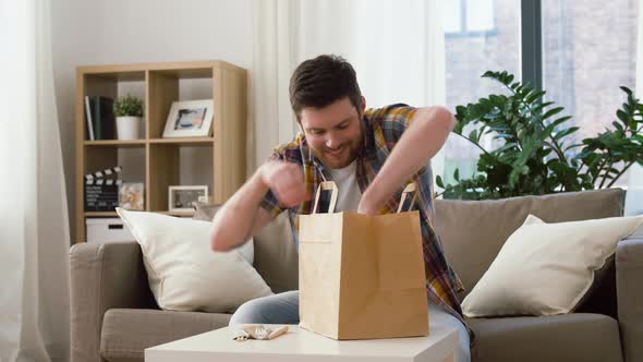 Smiling Man Unpacking Takeaway Food at Home