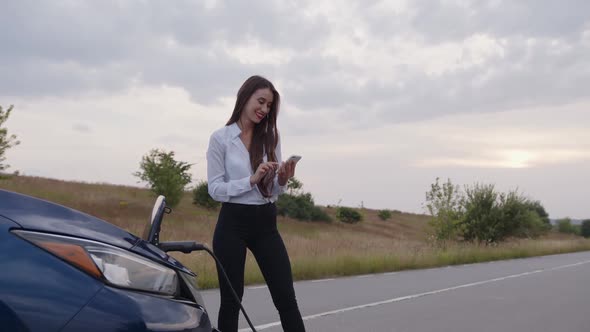 Smiling Girl Stands Near Her Charning Electric Car