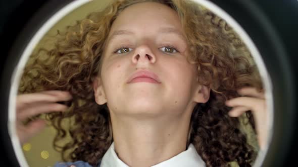 Portrait of a Teenage Girl Straightening Her Beautiful Curly Hair in Front of a Mirror