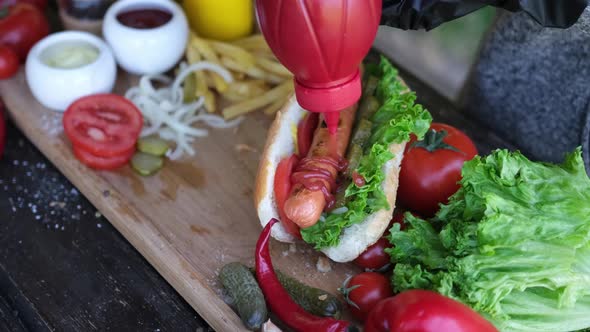 Making Hotdog  Woman Pouring Ketchup Tomato Sauce on Grilled Sausage
