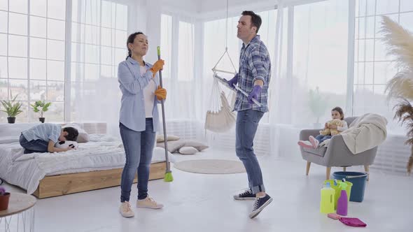 Cheerful Parents Dancing with Cleaning Devices