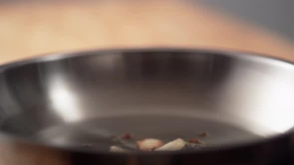 Camera follows cooking garlic with red pepper in olive oil. Slow Motion. alt