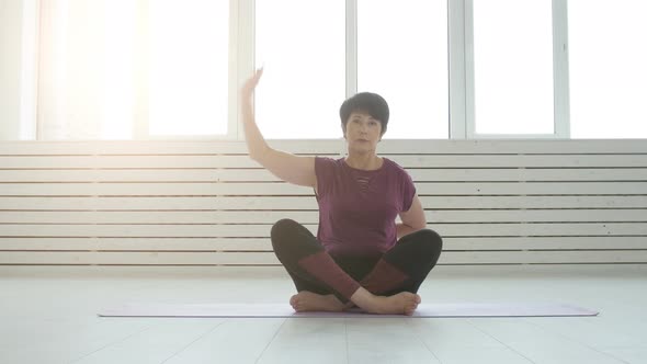 Concept of Harmony, Sport and Health. Middle-aged Woman Doing Yoga in a White Interior