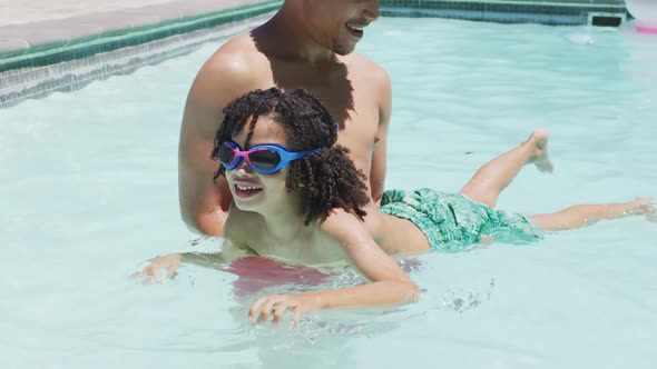 Happy biracial man and his son swimming in garden