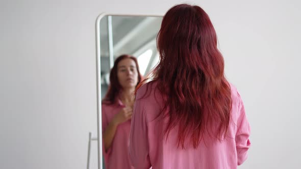 From the Back Woman Puts on Pink Shirt and Preens in Front of Mirror at Home