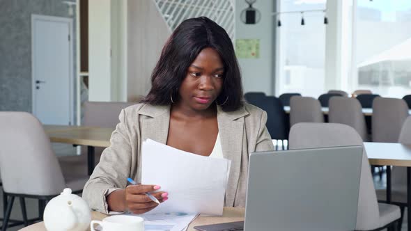 Black Business Lady Works with Papers and Laptop in Cafe