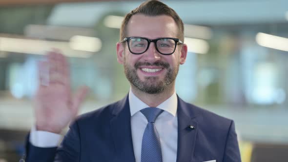 Portrait of Middle Aged Businessman Waving Welcoming