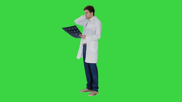 Frustrated Male Doctor Examining Computed Tomography Scan of Brain on a Green Screen, Chroma Key.