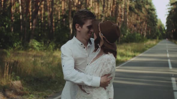 A Cheerful Young European Couple is Walking in a Picturesque Place in the Pine Forest with Soft