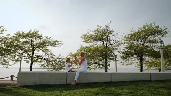 Mom and Daughter Playing Clapping Game in the Park at Sunset