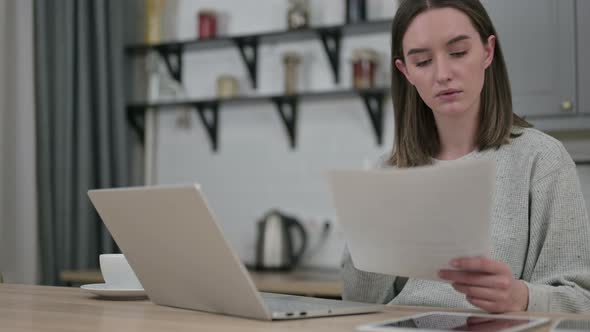 Focused Young Woman Using Laptop and Doing Paperwork 