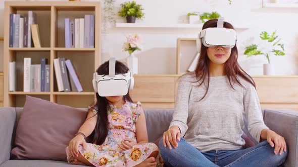 Asian mother and daughter are looking into virtual reality glasses, watching movies or online conten