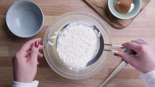 Baker Sifting Flour Through Fine Mesh Sieve For Cake Dough. - Top Down Shot