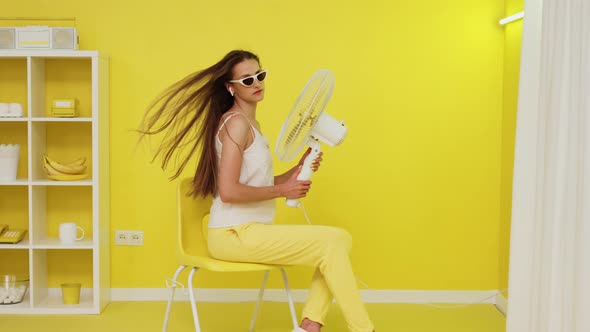 Sexy Woman With Electric Fan Is Posing On Chair