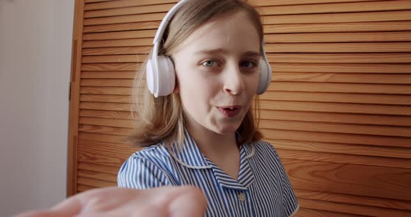 Teenage Girl Dancing and Smile with Wireless Headphones and Give Virtual Kiss