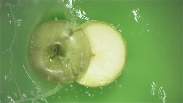 Green Apple Falling on Juice with Splash and Divided in Half