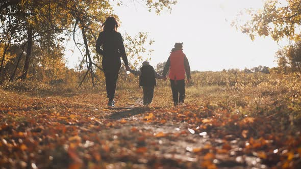 Mother and Two Children Walking in the Park and Enjoying the Beautiful Autumn Nature. Happy Family