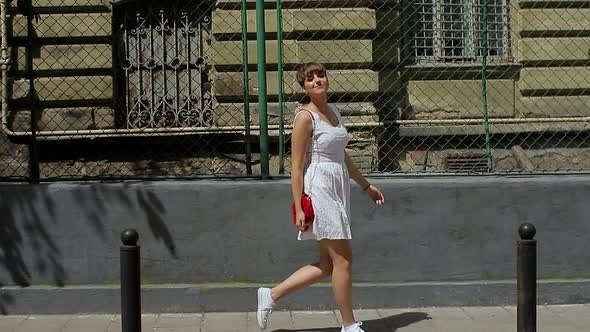 Beautiful Woman Smiling at Camera Enjoying Urban City Lifestyle. Young Funny Girl in a White Dress