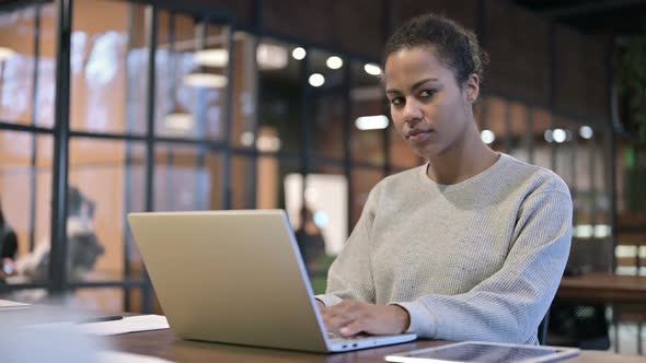 African Woman Working on Laptop Looking Toward Camera