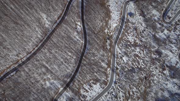 Aerial view of a car road surrounded by snow and trees in Greece.