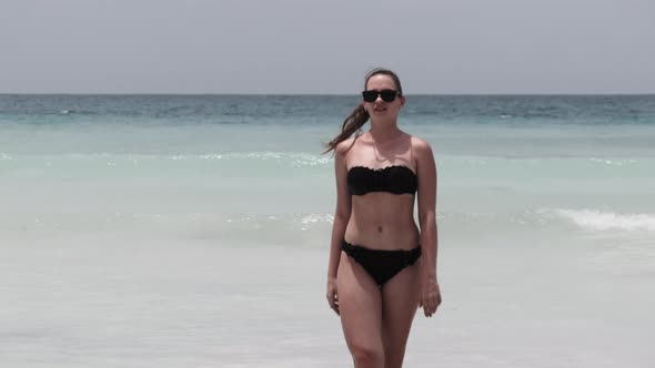 Young Woman in a Black Swimsuit Walks From the Turquoise Ocean on Paradise Beach