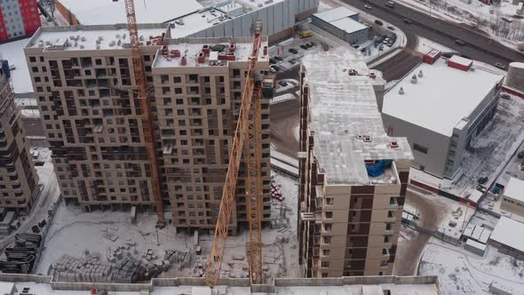 Yellow Tower Crane at Work at the Height of a Large Construction Site Against the Background of