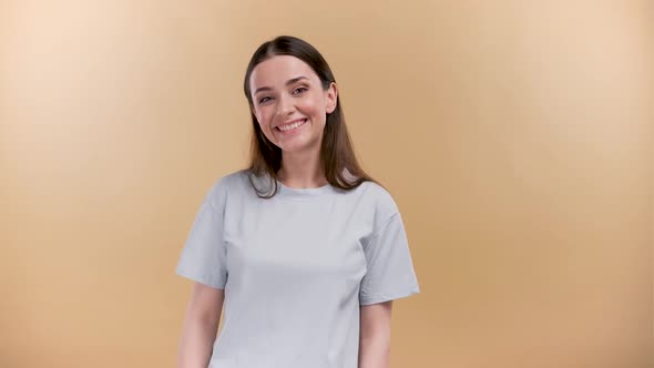 Cheerful Attractive Young Woman with Long Brown Hair Smiling and Winking at Camera Isolated Over