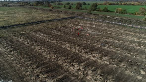 Field with Workers and Lots of Poles in Ground for Solar Panel Mounting Racks