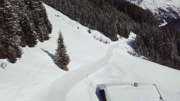 Aerial drone shot of snowy landscape, pathway in skiing area of Kleinwalsertal in the alps, Austria