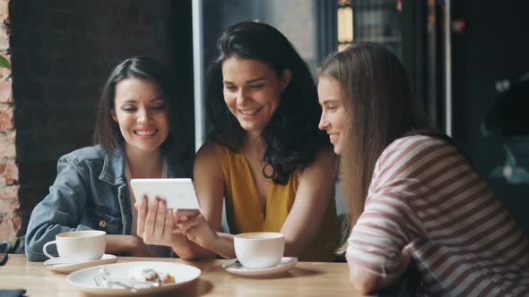 Happy Young People Watching Funny Content on Smartphone Screen in Cafe Laughing