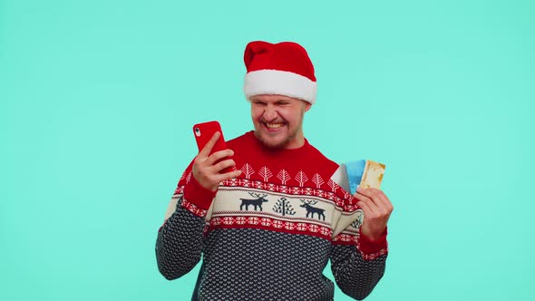 Man in Christmas Red Sweater Use Mobile Cell Phone Plastic Credit Bank Cards Win Calebrate Wow