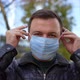 Calm Man Puts on Medical Mask While Looking at Camera at City Street - VideoHive Item for Sale
