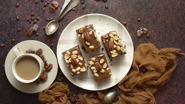 Chocolate Cake with Caramel Frosting Pecans and Hot Coffee on Rustic Background